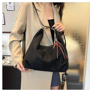Detail of black matte suede hobo bag with braided rope knot and gold key decoration