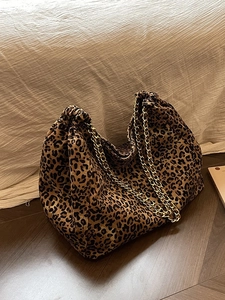 Large leopard print tote bag with golden chain straps on wooden floor, chic aesthetic
