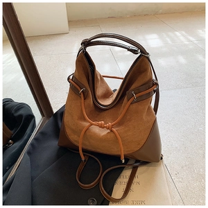 Detail of tan suede tote bag featuring smooth leather trim and orange drawstring accents
