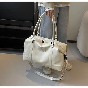 Detail of cream white travel bag showing crinkled leather texture and black zipper