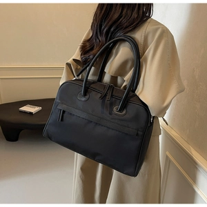 Seitenansicht einer großen schwarzen Nylon-Reisetasche mit Ledergriffen am Modell