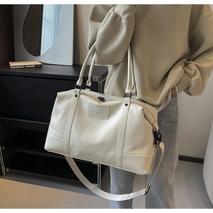 Close-up of a cream travel bag featuring lychee grain texture and adjustable strap