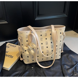 Gros plan du cabas beige avec motif ours et accessoire porte-clés ours assorti