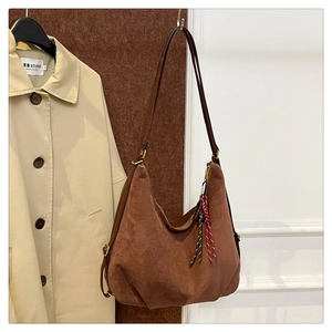 Brown faux suede hobo bag with leather strap and decorative woven tassel detail
