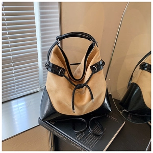 Detail of hobo bucket bag in brown suede and black patent leather with drawstring knot