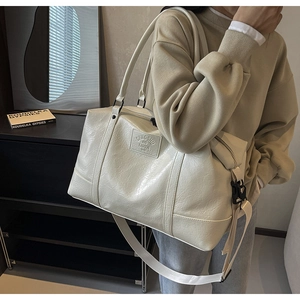 Detail of cream travel bag showing high-capacity design and textured faux leather surface