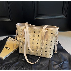 Détail d'un sac cabas beige avec motif ours posé sur une veste en cuir noir chic