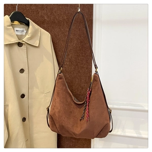 Detail of dark brown suede hobo tote bag featuring a slim shoulder strap and decorative lanyard