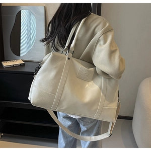 Detail of cream travel tote bag showing pebble leather texture and adjustable strap