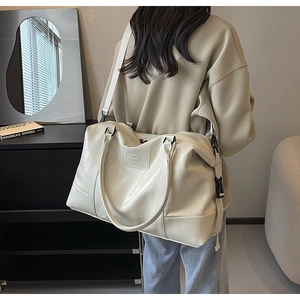 Lifestyle shot of large capacity off-white PU leather travel bag with wide shoulder strap
