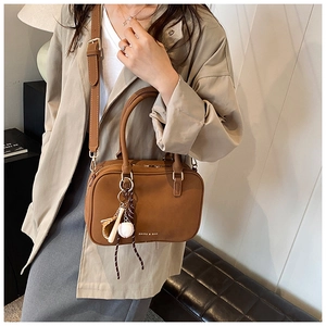 Dettaglio di una borsa Boston marrone con finitura in pelle e ciondolo da baseball creativo