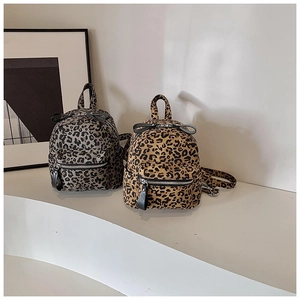 Close-up of mini leopard print backpacks in brown and grey tones on a white pedestal