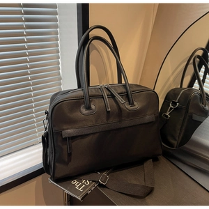 Detailansicht der großen schwarzen Reisetasche aus Nylon mit Riemen in Lederoptik