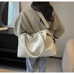 Detail of cream PU leather travel bag showing adjustable shoulder strap and texture