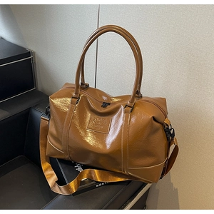 Close-up of caramel brown glossy travel bag with adjustable strap and embossed detail