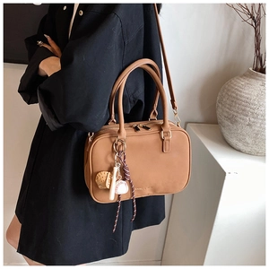 Borsa a spalla in pelle marrone con ciondolo sportivo e tracolla mostrata su modella