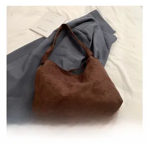 Close-up of a large dark brown suede tote bag featuring a minimalist semi-circular design