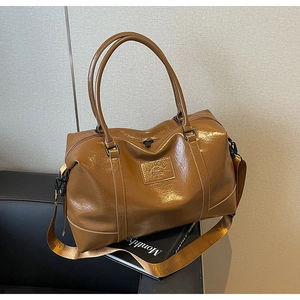 Close-up of brown glossy leather Boston travel bag with vintage texture and brand tag