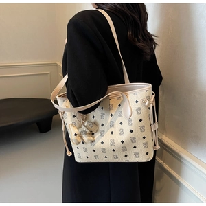 Gros plan du sac fourre-tout beige avec imprimés monogrammes et détails coulissants