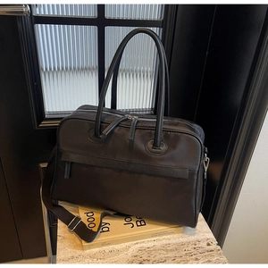 Detailansicht der schwarzen Reisetasche aus Nylon mit Ledergriffen auf Steinoberfläche