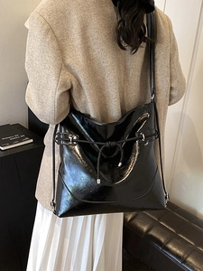 Glossy black faux leather large shoulder bag with drawstring detail on a model