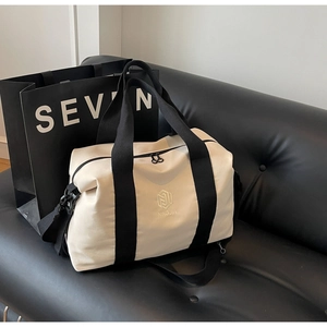 Détail du sac de voyage en toile beige avec sangles noires sur cuir luxueux