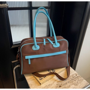 Nahaufnahme braune Reisetasche mit blauen Griffen und verstellbarem Schultergurt