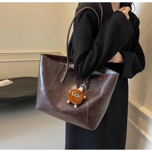 Detail der braunen Vintage-Tasche mit Knitter-Lederoptik und Plüschmonster-Anhänger