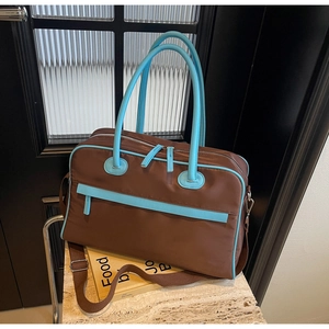 Detailansicht der braunen und himmelblauen Reisetasche mit Doppelgriffen und Gurt