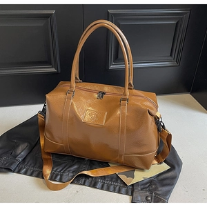 Detail of vintage brown leather travel bag with adjustable strap on leather jacket