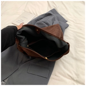 Close-up of brown suede tote bag interior with zipper pocket and golden magnetic closure