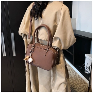 Dettaglio borsa Boston vintage marrone con manici tondi e ciondolo da baseball bianco
