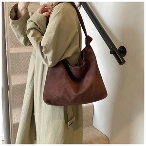 Detail of dark brown matte tote bag with decorative knot on shoulder strap shown on model