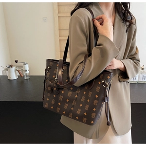Gros plan d'un grand sac cabas marron avec monogramme et pendentif cheval en cuir