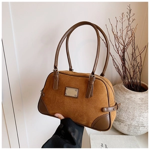 Dettaglio della texture scamosciata e cinturino in pelle marrone della borsa Boston