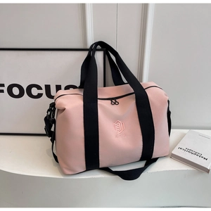 Détail du sac de voyage rose montrant le logo NINGJIA, le nylon et l'anse noire