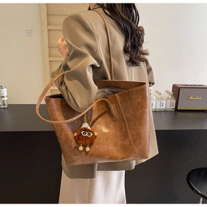 Braune Vintage-Ledershopper mit langen Trägern und einem Plüsch-Monster-Anhänger