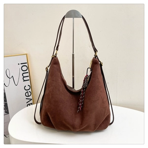 Detail of dark brown suede Hobo bag with a woven rope pendant and metal buckles