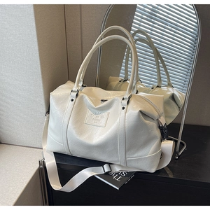 Close-up of cream white travel bag showing crinkled PU leather texture and embossed logo