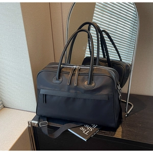 Detail einer großen schwarzen Reisetasche mit silbernen Reißverschlüssen und Gurt