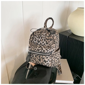 Close-up of leopard print mini backpack with zipper pockets on a stylish white display