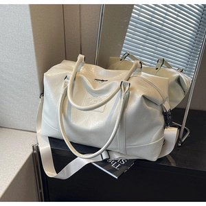 Detail of creamy white wrinkled faux leather texture and embossed logo on the travel bag