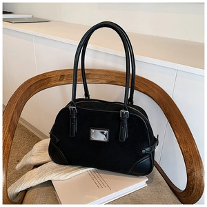 Dettaglio della borsa Boston nera vintage su sedia con trama scamosciata e targa argento