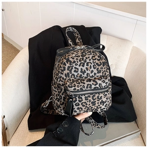 Close-up of leopard print mini backpack with decorative black bow and silver zipper details