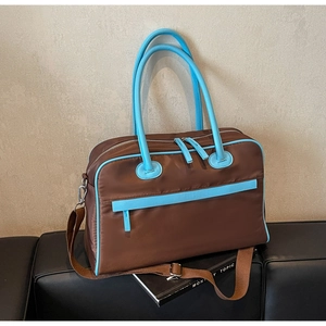 Detailansicht der großen braunen Nylon-Reisetasche mit blauem Besatz auf Ledersitz