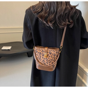 Dettaglio della borsa a secchiello leopardata con tracolla in pelle marrone sul modello
