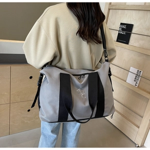 Grand sac de voyage gris porté par un mannequin montrant sa taille et son design