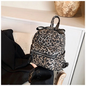 Detail of leopard print backpack with black leather bow and silver zipper accent