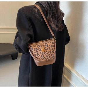 Frau im schwarzen Mantel mit Leoparden-Beuteltasche und braunem Lederbesatz-Detail