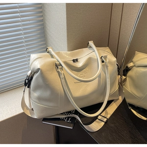 Detail of cream travel bag showing soft leather texture and adjustable shoulder strap